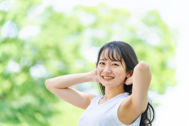 新緑の中で耳に手を当てている女性