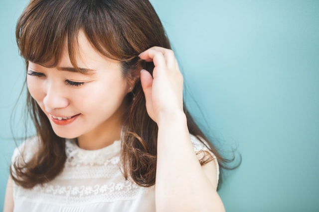 耳に手を当てる女性
