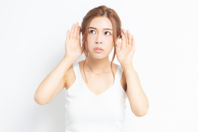 両耳に手を当てる女性