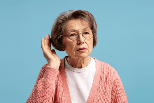 耳に手を当てて聞きかえす年配の女性