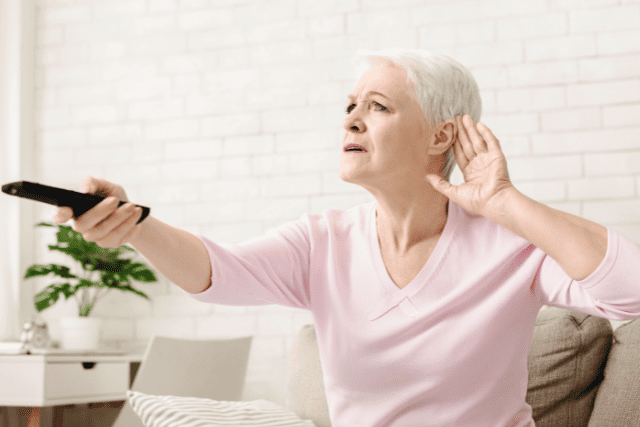 難聴を感じてテレビのボリュームを上げる高齢女性