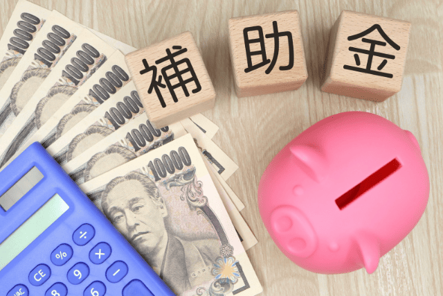「補助金」と書いてある積み木とお札と貯金箱