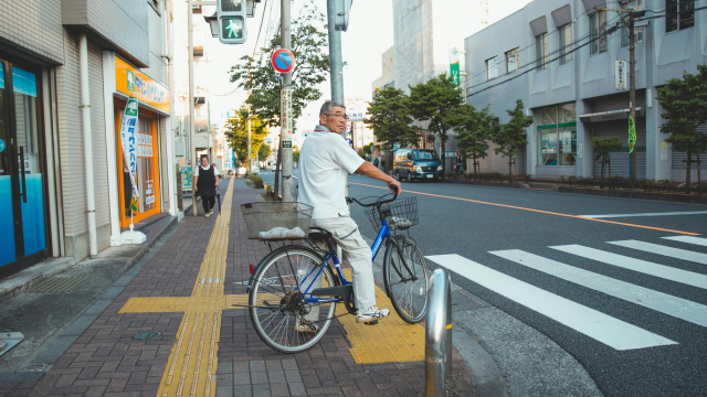 自転車を運転する老人が、横断歩道で信号待ちをしている様子