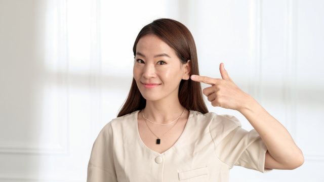 耳を指さしている女性