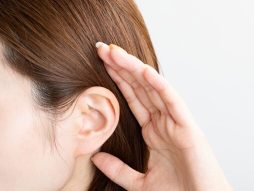 耳に手を当て聞いている女性