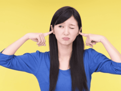 耳をふさぐ女性