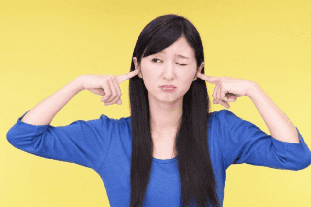 耳をふさぐ女性